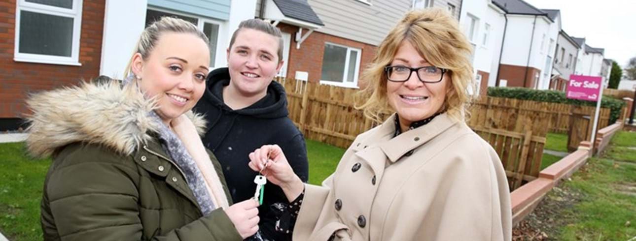 A Livin Staff member handing over the keys to two people outside their new property