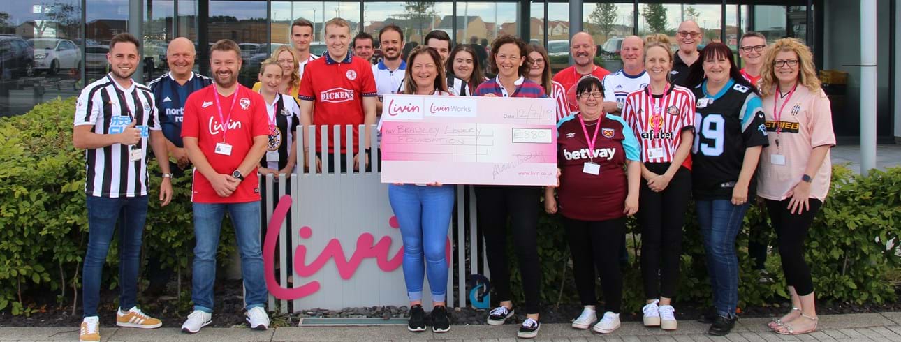 Livin's Bradley Lowery charity day featuring staff members in football tops holding a large cheque