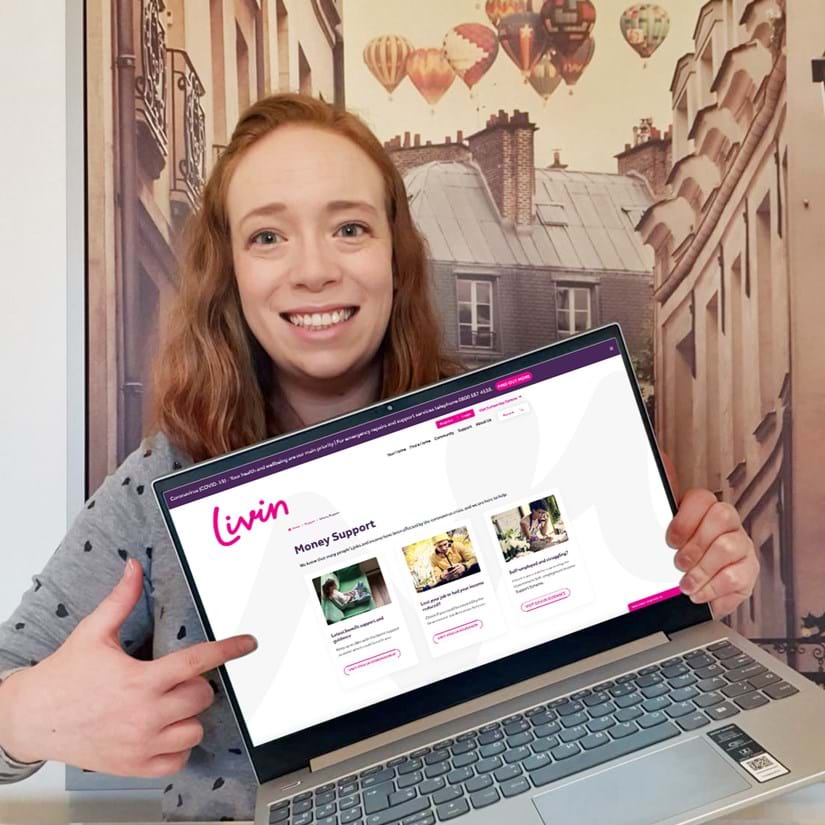 Livin staff member Victoria Wilkinson, Welfare Benefits Advisor holding a laptop with the Livin website on the screen