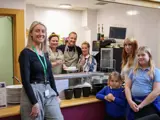 A group of people facing the camera in a community kitchen setting. 