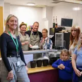A group of people facing the camera in a community kitchen setting. 