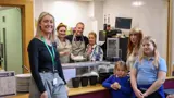 A group of people facing the camera in a community kitchen setting. 
