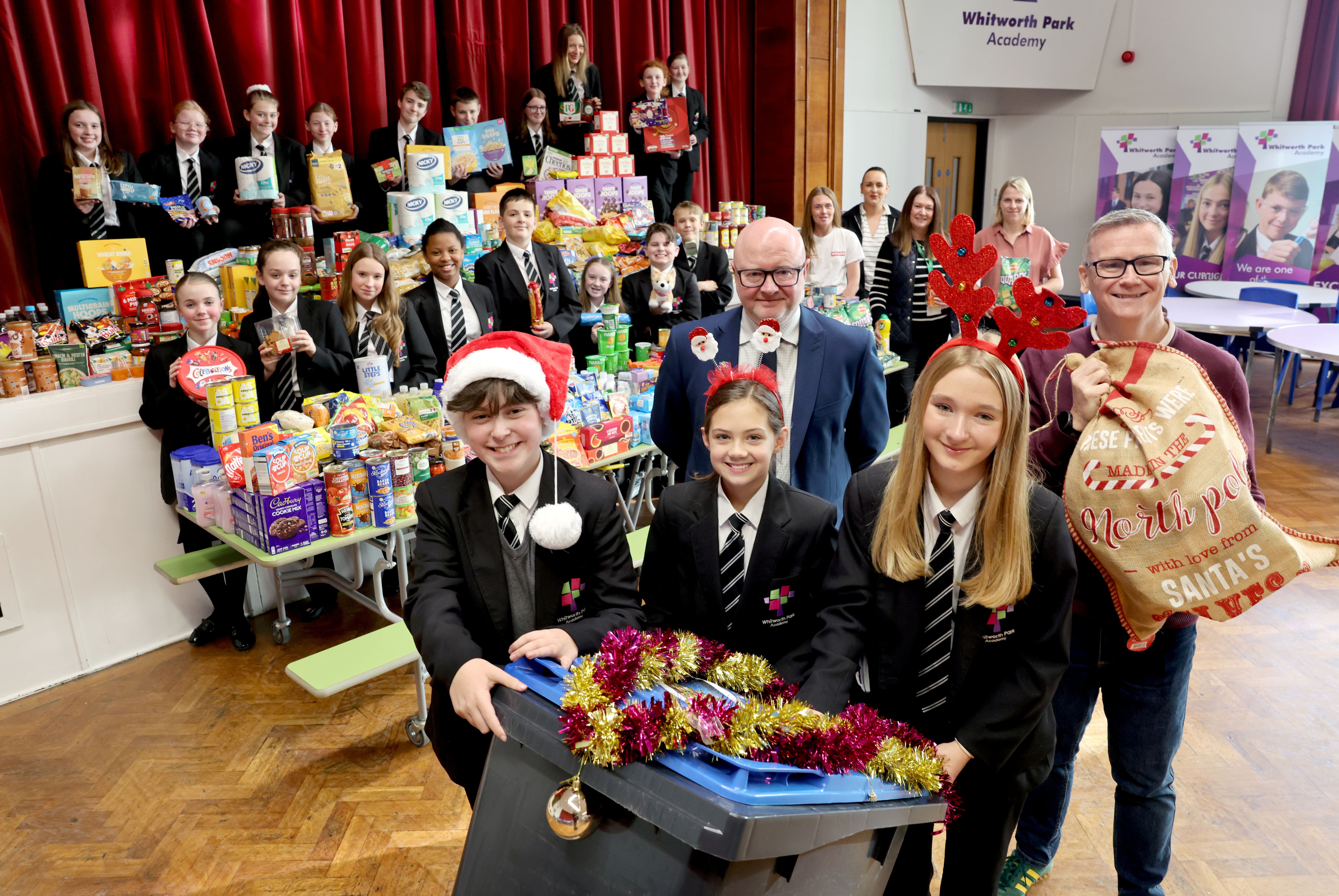 Students from Whitworth Park Academy and Livin staff gathered around food donated to several food banks