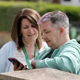 Our Financial Inclusion Manager speaking with a tenant whilst looking at their smartphone